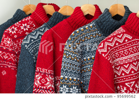 Collection of knitted Christmas turtleneck sweaters on hanger rack 95699562