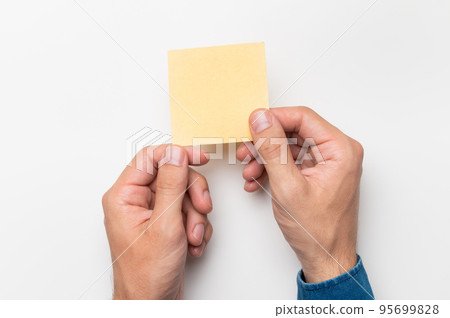 hands of an office worker hold colored stickers for notes on a white background, close-up hands of an office worker hold colored stickers for notes on a white background, close-up 95699828