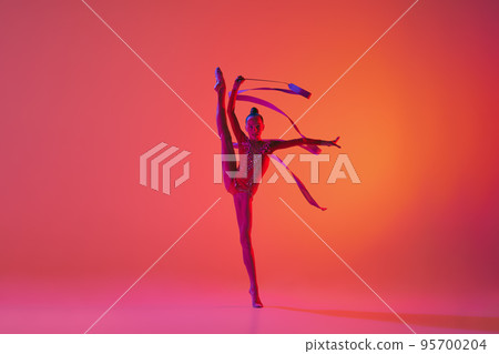 Beautiful and flexible graceful athlete rhythmic gymnastic artist dancing, doing stretch exercises isolated on colorful background in neon. Beauty, art, sport 95700204
