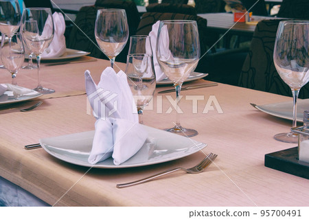 Wineglasses served for a festive dinner. Table setting in restaurant. Decorated holiday table. Luxury table settings for fine dining with glassware. Wineglasses served for a festive dinner. Table setting in restaurant. Decorated holiday table. Luxury table settings for fine dining with glassware. 95700491