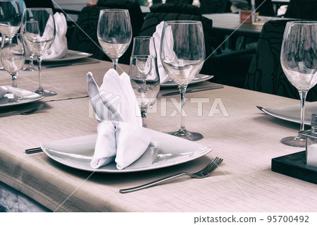 Wineglasses served for a festive dinner. Table setting in restaurant. Decorated holiday table. 95700492