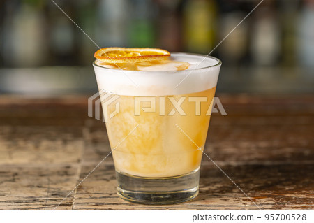 Vanilla Sour cocktail with egg white and lemon juice on the bar. Vanilla Sour cocktail with egg white and lemon juice on the bar. 95700528