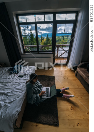 Female with laptop sitting on the floor and working on laptop 95701152