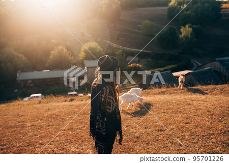 A female shepherd grazes goats on a meadow A female shepherd grazes goats on a meadow 95701226