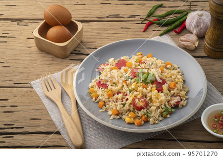Sausage Fried rice.Stir fried Thai rice with hot dog ,carrot and eggs in gray plate on wood table Sausage Fried rice.Stir fried Thai rice with hot dog ,carrot and eggs in gray plate on wood table 95701270