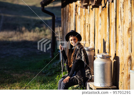 Woman sits on a bench with milk cans on a farm Woman sits on a bench with milk cans on a farm 95701291