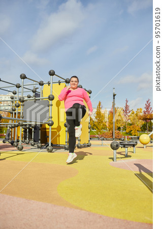 Outdoor training. Weight lost concept. Young woman doing fitness exercises at street public sports ground. Sunny autumn day. Sport, health, plans, body positive Outdoor training. Weight lost concept. Young woman doing fitness exercises at street public sports ground. Sunny autumn day. Sport, health, plans, body positive 95701619