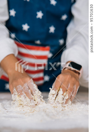 Young housewife in an apron kneads dough with her hands. 95701630