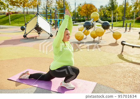 Outdoor training. Weight lost concept. Young woman doing fitness exercises at street public sports ground. Sunny autumn day. Sport, health, plans, body positive Outdoor training. Weight lost concept. Young woman doing fitness exercises at street public sports ground. Sunny autumn day. Sport, health, plans, body positive 95701634