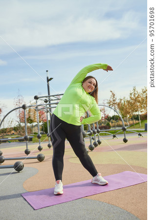 Outdoor training. Weight lost concept. Young woman doing fitness exercises at street public sports ground. Sunny autumn day. Sport, health, plans, body positive Outdoor training. Weight lost concept. Young woman doing fitness exercises at street public sports ground. Sunny autumn day. Sport, health, plans, body positive 95701698