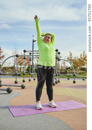 Outdoor training. Weight lost concept. Young woman doing fitness exercises at street public sports ground. Sunny autumn day. Sport, health, plans, body positive Outdoor training. Weight lost concept. Young woman doing fitness exercises at street public sports ground. Sunny autumn day. Sport, health, plans, body positive 95701700