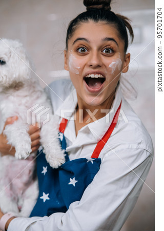 Smiling woman in kitchen holding cute white Maltese dog Smiling woman in kitchen holding cute white Maltese dog 95701704