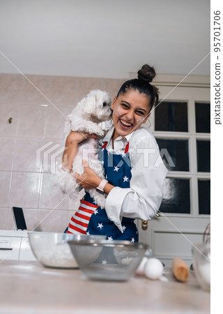 Smiling woman in kitchen holding cute white Maltese dog Smiling woman in kitchen holding cute white Maltese dog 95701706