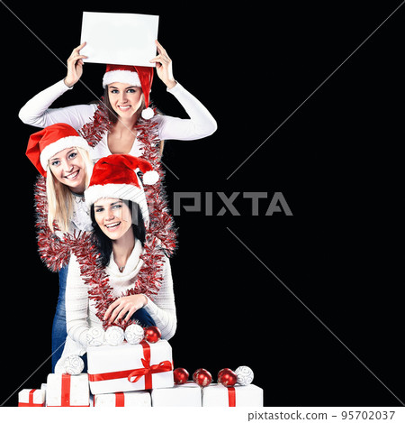 three young girls in costume of Santa Claus showing blank sheets 95702037