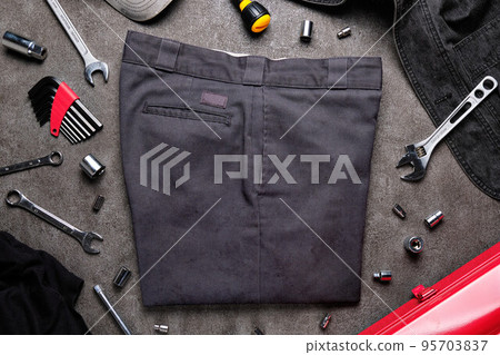 Dirty charcoal gray work pants and tools on concrete Dirty charcoal gray work pants and tools on concrete 95703837