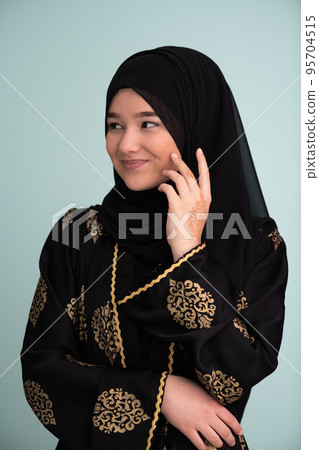 beautiful muslim woman in fashinable dress with hijab isolated on modern cyan background representing concept of modern islam and ramadan kareem 95704515