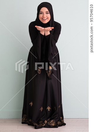 beautiful muslim woman in fashinable dress with hijab isolated on modern cyan background representing concept of modern islam and ramadan kareem 95704610