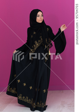 beautiful muslim woman in fashinable dress with hijab isolated on modern pink background representing concept of modern islam and ramadan kareem 95704703