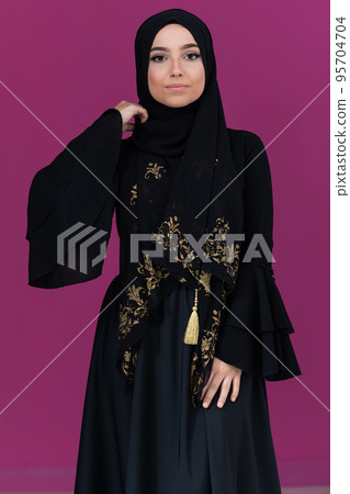 beautiful muslim woman in fashinable dress with hijab isolated on modern pink background representing concept of modern islam and ramadan kareem 95704704