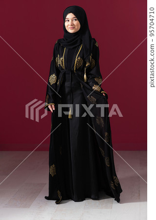 beautiful muslim woman in fashinable dress with hijab isolated on modern red background representing concept of modern islam and ramadan kareem 95704710