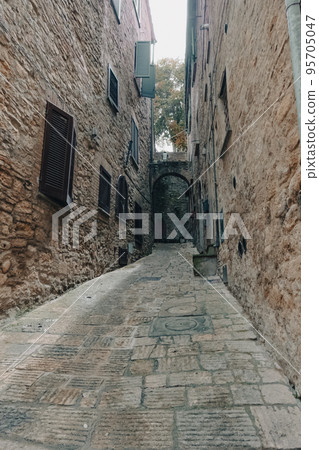 Narrow alley of a medieval town in Tuscany, Italy 95705047