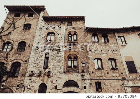 Front facade of aged medieval buildings of San Gimignano 95705084