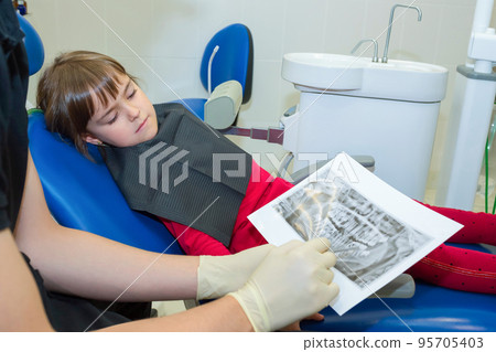 A dentist and a child patient are looking on dental X-rays 95705403