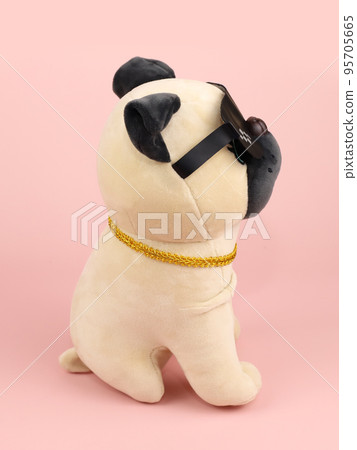 Plush soft beige black pug dog toy with sunglasses isolated on pink background. Side view, close-up 95705665
