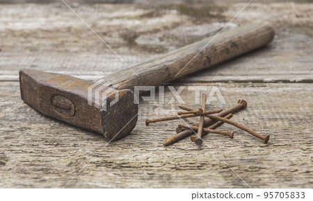 Old rusty hammer and nails on an unpainted wooden table Old rusty hammer and nails on an unpainted wooden table 95705833