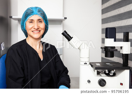 Female scientist looking at slides with patient samples using an inverted microscope in the laboratory. 95706195