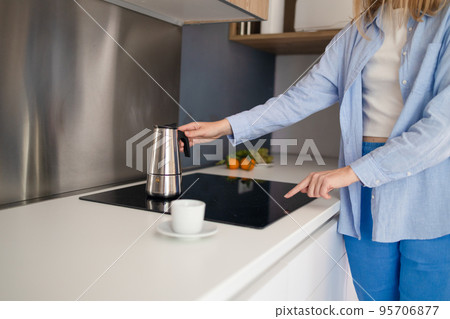 Cropped photo of a woman hands pouring coffee from a pot while standing in the kitchen. Having breakfast in the morning 95706877
