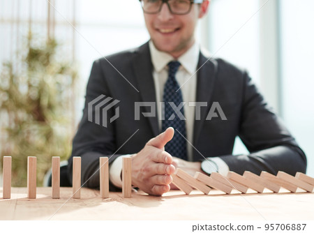 Businessman with dominoes in the office. concept business risk Businessman with dominoes in the office. concept business risk 95706887