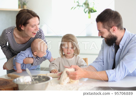 Young parents playing with children in the kitchen 95706889