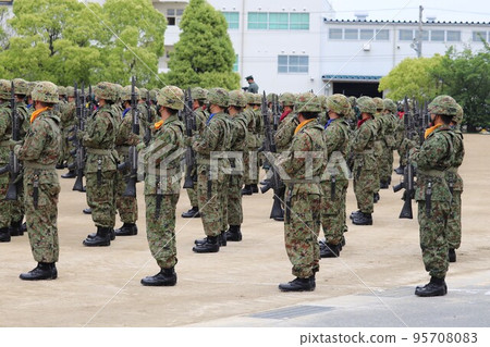 A member of the Ground Self-Defense Force who makes an offering with a Type 89 rifle 95708083