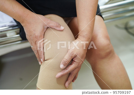 Asian senior woman wearing elastic support knee brace for reduce pain. Asian senior woman wearing elastic support knee brace for reduce pain. 95709197