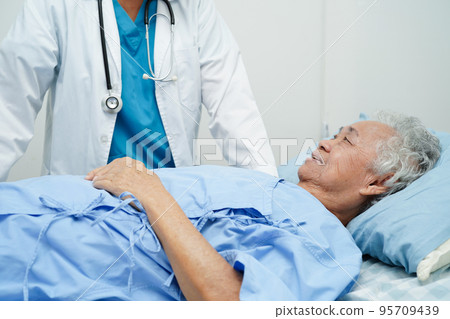 Doctor taking care, help and encourage Asian elder senior woman patient in clinic hospital. 95709439