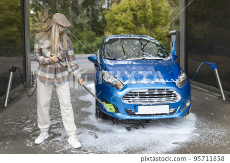 the women herself at the car wash washes the car with a brush 95711858