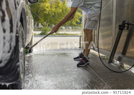 the man herself at the car wash washes the car with a brush the man herself at the car wash washes the car with a brush 95711924