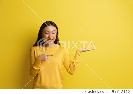 Smiling Woman Pointing Aside. Amused Young Girl Points Finger Away Smiling Woman Pointing Aside. Amused Young Girl Points Finger Away 95712440