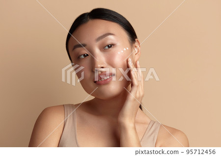 Skin Care Woman Applying Cream on Cheek. Asian Girl Putting Cream On Skin 95712456