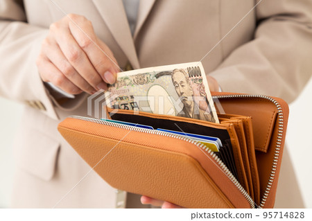 A middle-aged woman in a suit taking out money from her wallet 95714828