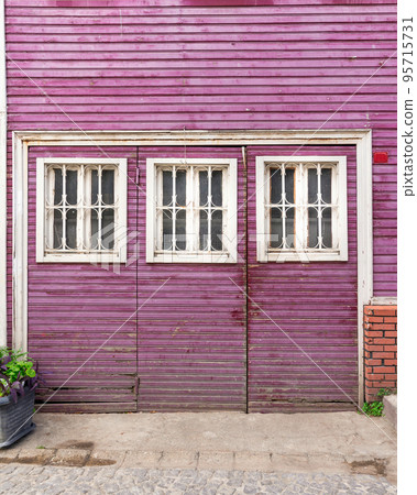 Wooden grunge weathered abandoned door painted in purple, with three white wooden windows painted in white 95715731