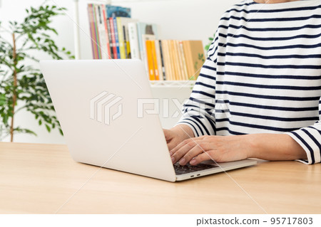 在房間裡操作電腦的休閒中年婦女 95717803
