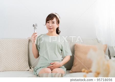 Japanese pregnant woman with spoon and fork (gluttony / meal) Japanese pregnant woman with spoon and fork (gluttony / meal) 95718056