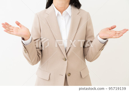 A middle-aged woman in a suit who spreads her hands and raises her hands 95719139