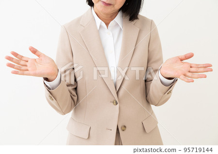 A middle-aged woman in a suit who spreads her hands and raises her hands 95719144