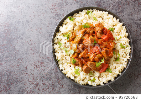 Porkolt is a delicious Hungarian meat stew cooked in a savory paprika tomato onion sauce served with Egg Noodles closeup on the plate. Horizontal top view 95720568