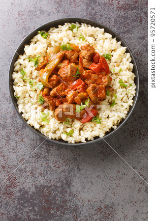 Porkolt is a classic Hungarian cuisine beef stew with onions and plenty of paprika close-up in a plate. Vertical top view Porkolt is a classic Hungarian cuisine beef stew with onions and plenty of paprika close-up in a plate. Vertical top view 95720571