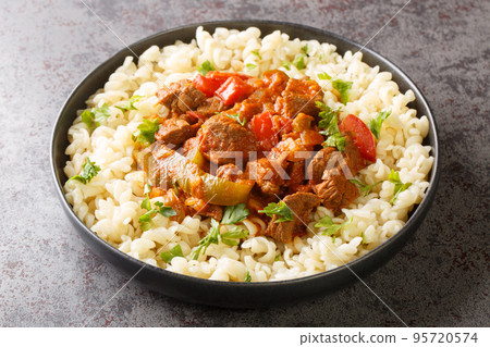 Porkolt is a delicious Hungarian meat stew cooked in a savory paprika tomato onion sauce served with Egg Noodles closeup on the plate. Horizontal Porkolt is a delicious Hungarian meat stew cooked in a savory paprika tomato onion sauce served with Egg Noodles closeup on the plate. Horizontal 95720574