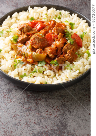 Porkolt Hungarian Beef and Onion Stew with Egg Noodles Nokedli closeup on the plate. Vertical 95720577